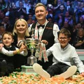 England's Kyren Wilson poses with the trophy, his wife Sophie and his sons Bailey (L) and Finley (R) after victory over Wales' Jak Jones. (Photo by OLI SCARFF/AFP via Getty Images)