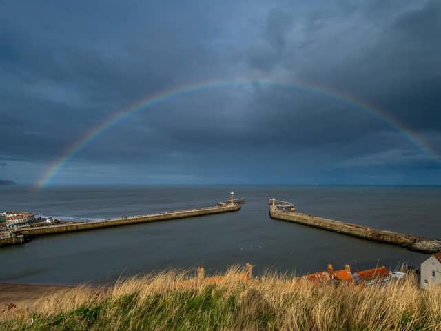A rainbow stretching over Whitby's harbour walls brightens up the dark sky. PIC: James Hardisty