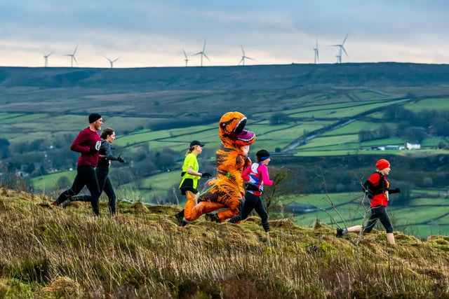 A group of runners race along the moors, including a participant dressed as a dinosaur.