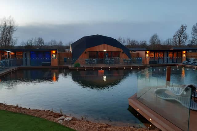 The spa setting is lit up at night adding to the magical appearance of the spa buildings and wild swimming pool.