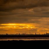 A glowing sky silhouettes the skyline of Hull's docks and chemical plants.