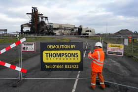 A worker adjusts a fence as the remains of the Pulverised Coal Injection (PCI) plant lie on the ground after an explosive demolition at the Teesworks site on October 19, 2022 in Redcar.