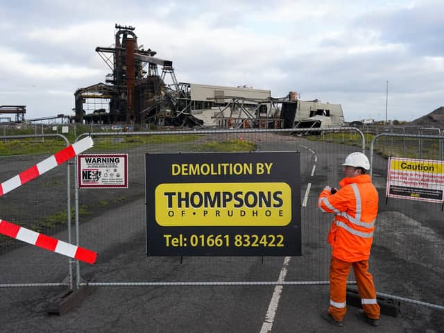 A worker adjusts a fence as the remains of the Pulverised Coal Injection (PCI) plant lie on the ground after an explosive demolition at the Teesworks site on October 19, 2022 in Redcar.