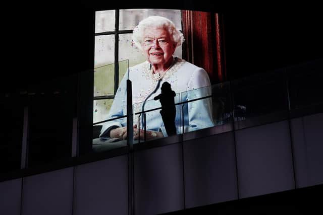 A person stands along the Las Vegas Strip as an image of Queen Elizabeth II is shown on a casino marquee Thursday, Sept. 8, 2022, in Las Vegas. (AP Photo/John Locher)