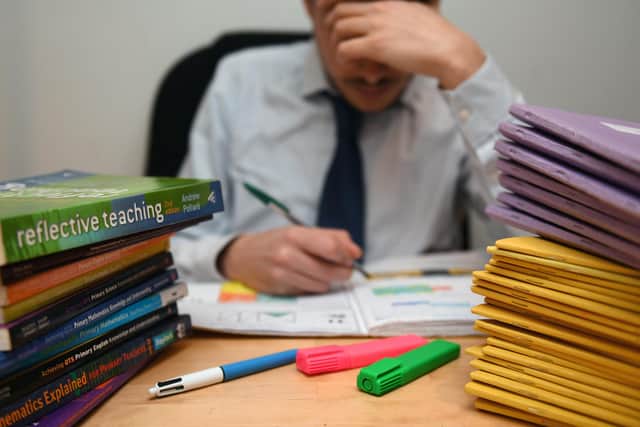 A primary school teacher looking stressed next to piles of classroom books. PIC: PA/PA Wire