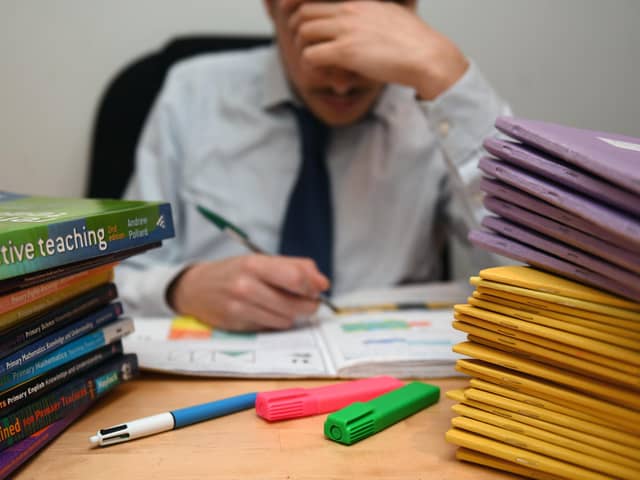 A primary school teacher looking stressed next to piles of classroom books. PIC: PA/PA Wire
