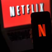 A computer screen and mobile phone display the Netflix logo. Photo by OLIVIER DOULIERY/AFP via Getty Images.