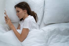 A woman in bed looking at her phone. Picture: Alamy/PA.