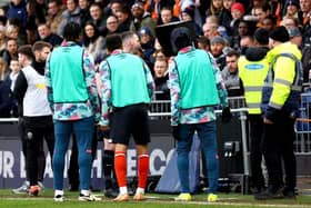 WAITING GAME: Luton Town substitutes watch on as referee Chris Kavanagh reviews the pitchside monitor during the Premier League match against Sheffield United