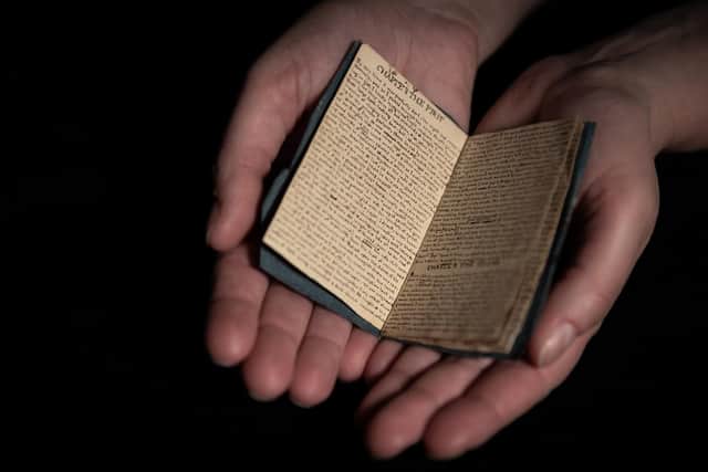 A curator cradles ‘Visits in Verreopolis’, a miniature, handwritten book by Charlotte Brontë. Photo:Mark Webster Photography/University of Leeds.