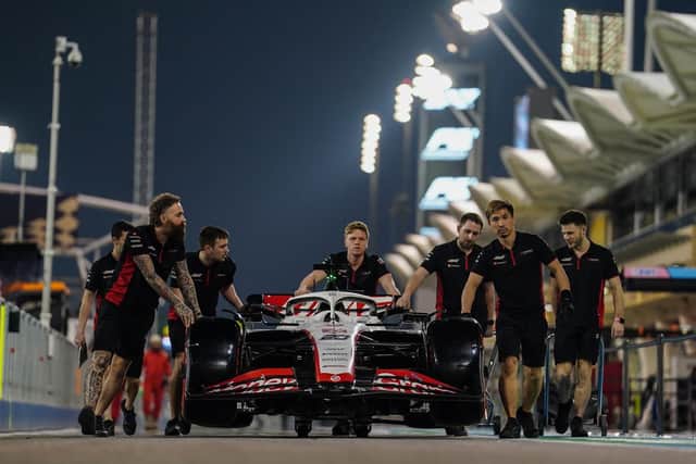 GREEN LIGHT: Haas mechanics push Kevin Magnusson's car to be weighed during preview day of the Bahrain Grand Prix at the Bahrain International Circuit. PIcture: David Davies/PA