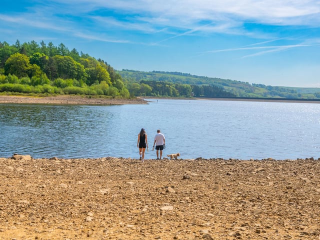 Isobel Meldrum, 25, with friend Joe Shayler of Menston, near Leeds, walking their Cockapoo around the dried edge of Swinsty Reservoir. Picture: James Hardisty