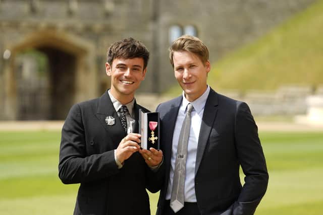 Tom Daley (left) after receiving his OBE in 2022 with his husband, Dustin Lance Black. Picture credit: Alamy/PA.