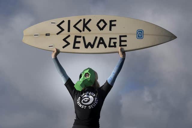 A representative from Surfers against Sewage protests against sewage discharges at an overflow pipe on Long Rock Beach in Penzance, Cornwall