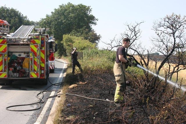 A firefighter sprays a jet of water onto a roadside fire in South Yorkshire.