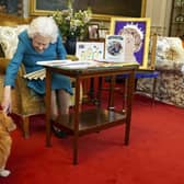 Queen Elizabeth II being joined by one of her corgis. (Pic credit: Steve Parsons / PA)