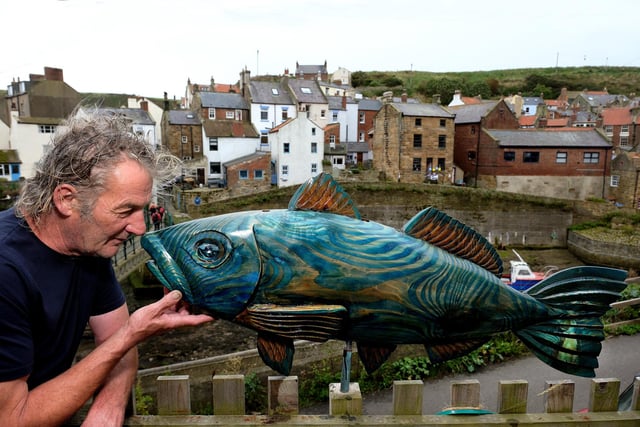 Sculptor Steve Iredale with one of his sculptures and the backdrop of Staithes