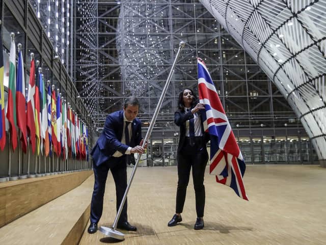 EU Council staff members remove the United Kingdom's flag from the European Council building in Brussels on Brexit Day, January 31, 2020. (Photo by OLIVIER HOSLET / POOL / AFP)