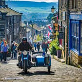 A motorcycle and sidecar travel on the cobbles on Main Street in Haworth. (Pic credit: Tony Johnson)