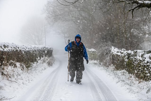 A man walks in the snow covered lane in Queensbury, West Yorkshire