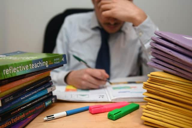 School teacher next to piles of classroom books. (Pic credit: PA Wire)