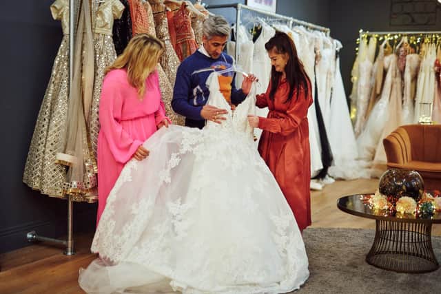 Tan France looks at a wedding dress. Photo: JACOB NIBLETT/© 2023 Warner Bros. Discovery, Inc. or its subsidiaries and affiliates. All rights reserved.