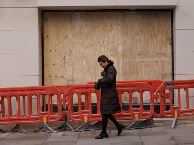 A member of the public walks past a boarded up shop on New Bond Street in London.