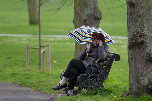 Library image of a woman sheltering from the rain in Greenwich Park, London, during April. (Photo by Yui Mok/PA Wire)