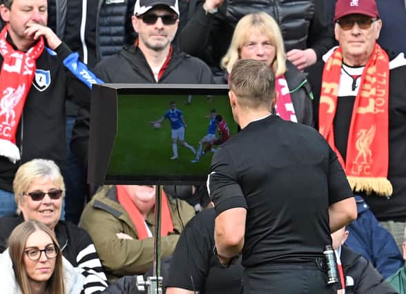 Referee Craig Pawson looks at a replay on a monitor during a VAR review, before awarding a penalty to Liverpool, during the English Premier League football match between Liverpool and Everton at Anfield in Liverpool, north west England on October 21, 2023. (Photo by Paul ELLIS / AFP) / RESTRICTED TO EDITORIAL USE. No use with unauthorized audio, video, data, fixture lists, club/league logos or 'live' services. Online in-match use limited to 120 images. An additional 40 images may be used in extra time. No video emulation. Social media in-match use limited to 120 images. An additional 40 images may be used in extra time. No use in betting publications, games or single club/league/player publications. /  (Photo by PAUL ELLIS/AFP via Getty Images)
