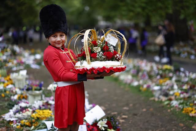Eight year old Ruya Anastasia Dibek from Llaanelli in Wales poses with flowers at a memorial site in Green Park near Buckingham Palace (Photo by Jeff J Mitchell/Getty Images)