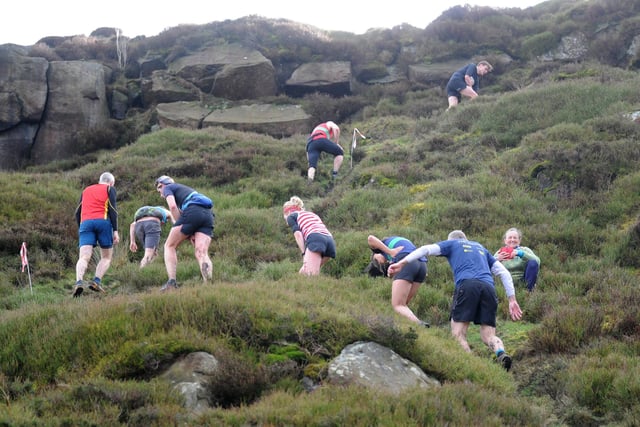 Runners run down the rocks in Ilkley Moor.