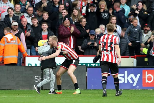 PARTY TIME: Sheffield United's Oli McBurnie embraces a young pitch invader after scoring the equalising goal against Championship rivals Norwich City at Bramall Lane, Sheffield. Picture: Barrington Coombs/PA