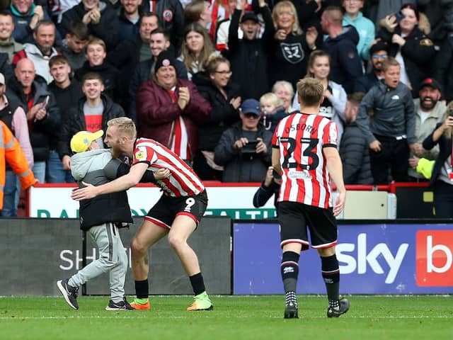 PARTY TIME: Sheffield United's Oli McBurnie embraces a young pitch invader after scoring the equalising goal against Championship rivals Norwich City at Bramall Lane, Sheffield. Picture: Barrington Coombs/PA