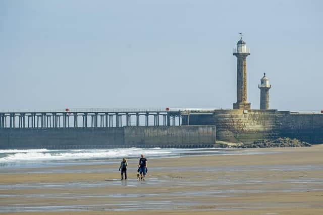 A couple take a walk on the beach at the towns West Cliff, Whitby.  (Pic credit: Tony Johnson)