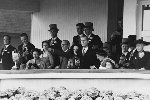 Queen Elizabeth II (head just visible, right), the Duke of Edinburgh (standing holding binoculars, centre), Princess Margaret (fourth left) and her partner RAF Group Captain Peter Townsend (standing, no hat), in the Royal Box at Royal Ascot races in June 1952. (Photo by Central Press/Hulton Archive/Getty Images)