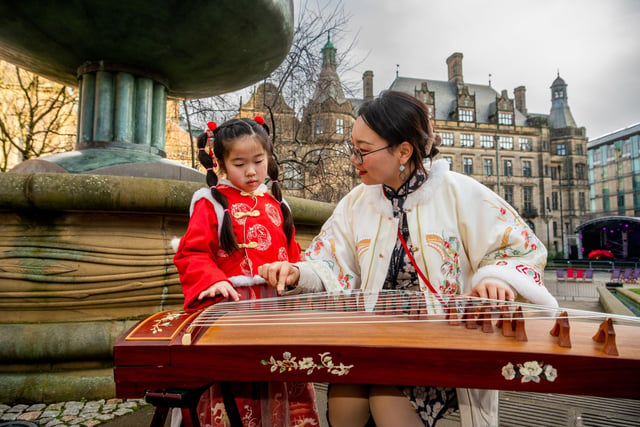Chloe Wei, age 6, from Manchester wearing a Tang Chinese costume whilst visiting the festival and learning how to play a traditional Chinese instrument called the Guzheng by Jocelyn Li, a language teacher at Sheffield University.