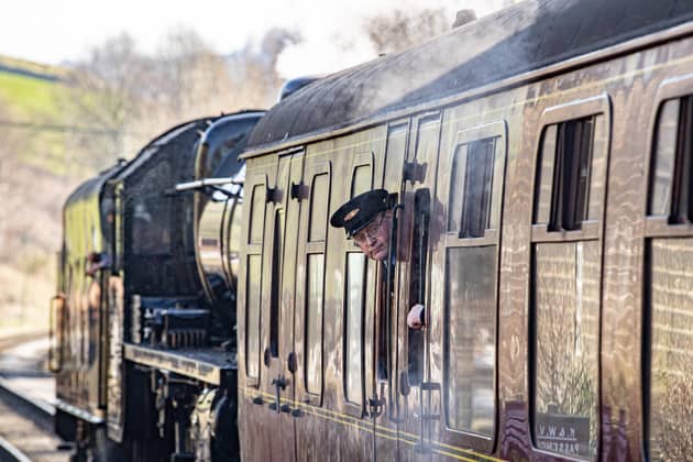 A guard on duty pictured looking out of a carriage leaving Oakworth Station on the first day of the annual Steam Gala weekend on the Keighley and Worth Valley Railway.