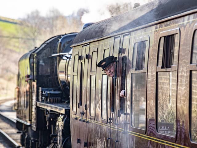 A guard on duty pictured looking out of a carriage leaving Oakworth Station on the first day of the annual Steam Gala weekend on the Keighley and Worth Valley Railway.