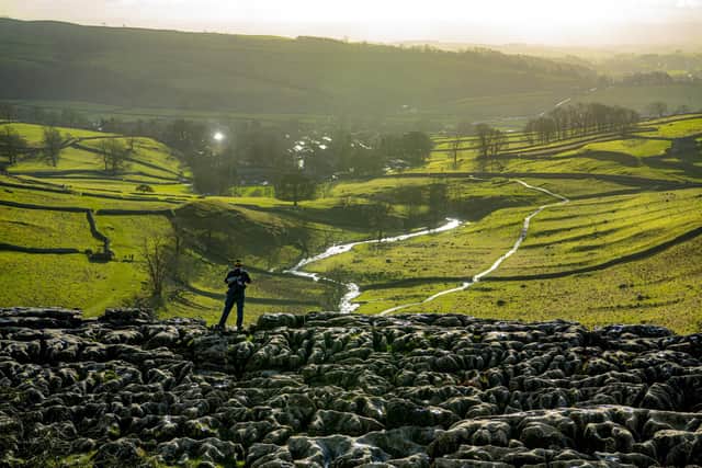 A walker admires the views onto Malham whilst standing on the clints and grykes at the top of Malham Cove in the Yorkshire Dales National Park. Picture Tony Johnson