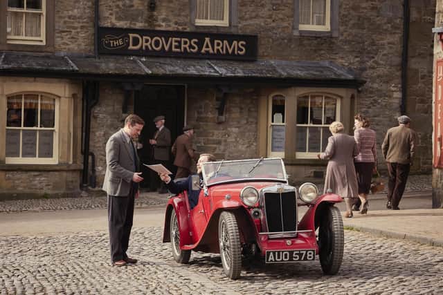This red car and its driver were was spotted in Grassington AKA Darrowby back in March. Nicholas Ralph (James Herriot) Caolan McCarthy (Granville Bennett). ©5 Broadcasting Limited / © Playground Television UK Ltd. 2026 / Photographer: Helen Williams