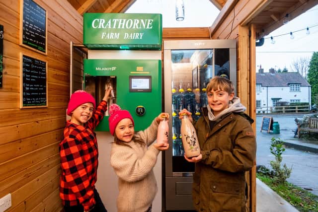 Pictured Stan, 9, Clemmie, 6, and Wilf, 11, Dugdale, purchasing milk and milk shakes from the dispenser next to the post office.