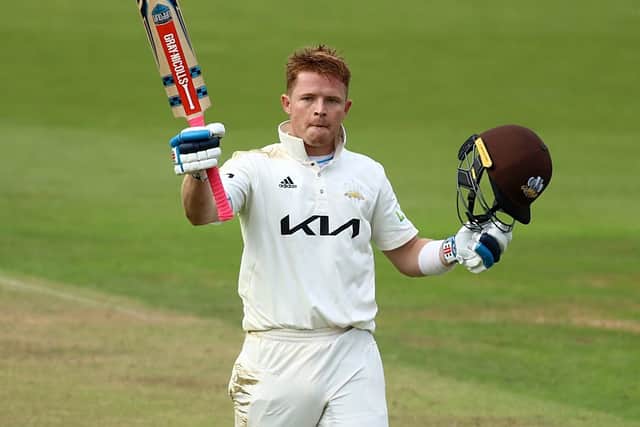 Ollie Pope raises his bat after reaching three figures. Photo by Ben Hoskins/Getty Images for Surrey CCC