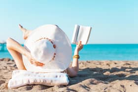 A woman reading on a beach. PIC: Alamy/PA