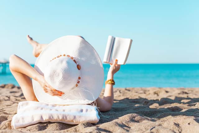 A woman reading on a beach. PIC: Alamy/PA
