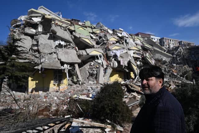 TOPSHOT - A man waits for a rescue team next to his collapsed building in the southeastern Turkish city of Kahramanmaras, on February 8, 2023, two days after a strong earthquake struck the region. - Searchers were still pulling survivors on February 8 from the rubble of the earthquake that killed over 11,200 people in Turkey and Syria, even as the window for rescues narrowed. For two days and nights since the 7.8 magnitude quake, thousands of searchers have worked in freezing temperatures to find those still alive under flattened buildings on either side of the border. (Photo by OZAN KOSE / AFP) (Photo by OZAN KOSE/AFP via Getty Images)