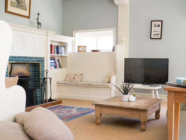 A cosy dual aspect sitting room with an open fireplace.