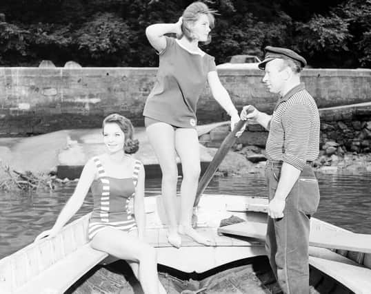 Two models in bathing suits pose with Val Padura, the Cramond ferry man, in 1962.