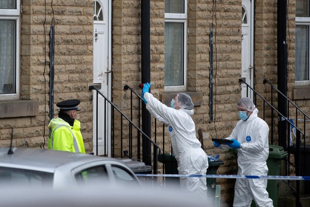 Crime scene investigations officers inspect what appears to be blood on the door handle of a property where a woman was found seriosuly injured and died after a man was arrested for murder in Ravensthorpe, Dewsbury.