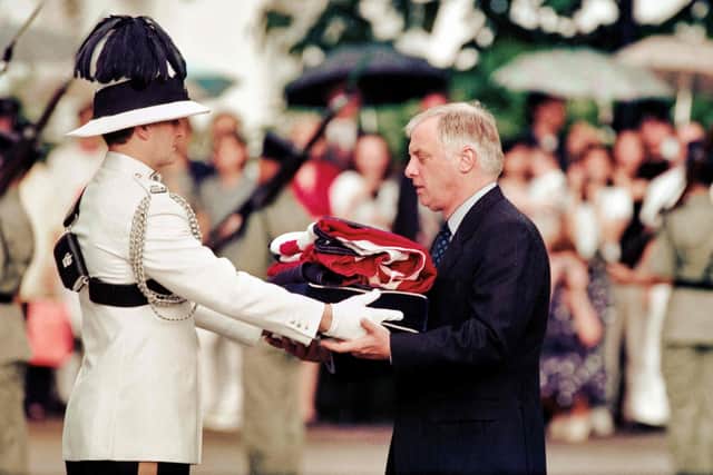 Chris Patten (R), the 28th and last governor of colonial Hong Kong, receives the Union Jack flag after it was lowered for the last time at Government House - the governor's official residence - during a farewell ceremony in Hong Kong on June 30, 1997, just hours prior to the territory's handover from British to Chinese rule.  (Photo by EMMANUEL DUNAND/AFP via Getty Images)