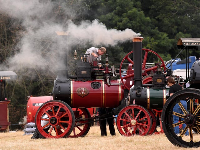 Steam rises from a vintage traction engine as exhibitors carry out last-minute preparations before it heads into action
